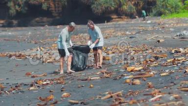 群志愿者清理沙滩.. 志愿者举起并把一个塑料垃圾扔进袋子里。 环境